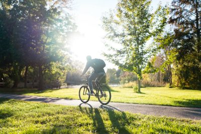 Bicyclist on Virginia Tech’s Blacksburg campus with the sun peaking through the trees.