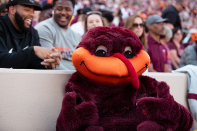 the HokieBird gives a thumbs up in front of packed stands 